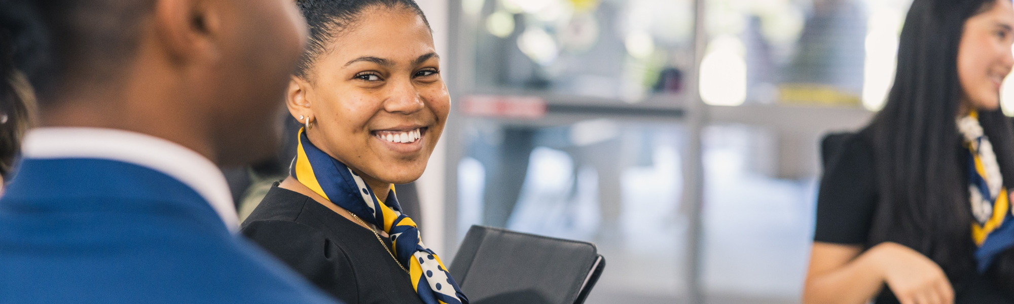 A female student in business attire holding a notepad